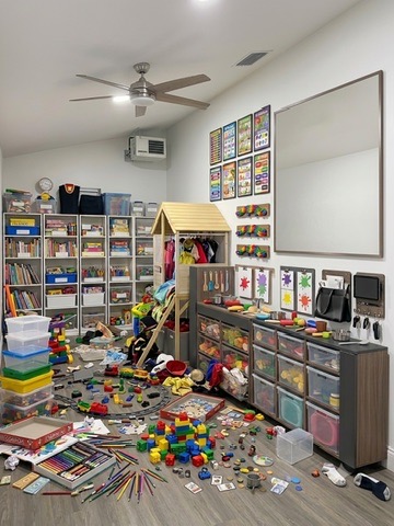 Kids playroom before organizing — toys, books, and bins scattered across the floor